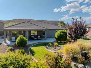 Rear view of property featuring outdoor furniture, a patio area, stucco siding, a mountain view, and a yard