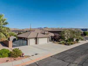 Ranch-style house with an attached garage, a mountain view, concrete driveway, stucco siding, and a gate