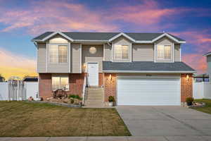 Split foyer home featuring a garage, driveway, brick siding, and a shingled roof