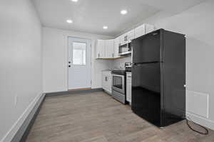 Kitchen featuring stainless steel appliances, white cabinetry, dark wood-style floors, and recessed lighting