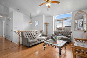 Living area featuring plenty of natural light, ceiling fan, wood finished floors, and a textured ceiling