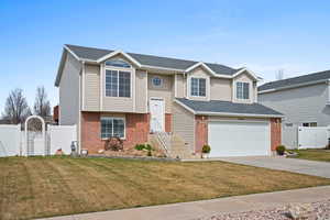 Bi-level home with a gate, brick siding, concrete driveway, and a shingled roof