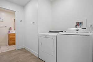 Laundry area with light wood-style flooring and washer and dryer