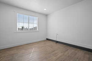 Spare room featuring dark wood-type flooring, a textured ceiling, and recessed lighting