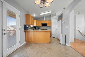 Kitchen featuring lofted ceiling, a peninsula, light countertops, freestanding refrigerator, and tasteful backsplash