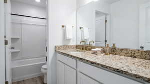 Bathroom with vanity, light wood-style floors, and washtub / shower combination