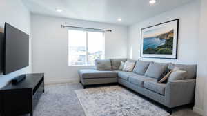 Living area with light carpet and recessed lighting