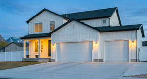 Modern inspired farmhouse with board and batten siding, concrete driveway, roof with shingles, and a garage