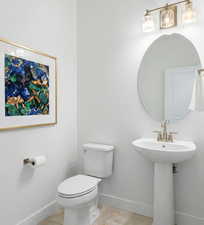 Half bathroom with toilet and baseboards off of entry