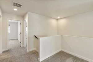 Hall with light colored carpet and recessed lighting