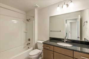 Full bathroom with a textured ceiling, vanity, and shower / bath combination