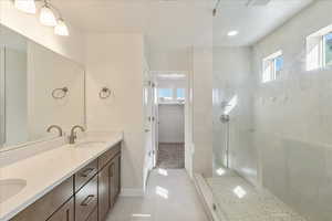 Full bath with a walk in closet, double vanity, a walk in shower, and light tile patterned flooring
