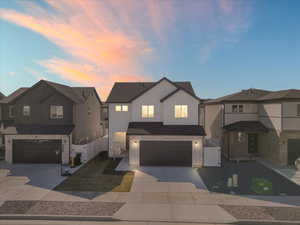 View of front of home featuring a gate, board and batten siding, concrete driveway, and an attached garage