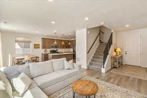 Living room with light wood finished floors, recessed lighting, and a textured ceiling