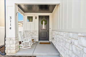 Entrance to property with a porch and stone siding