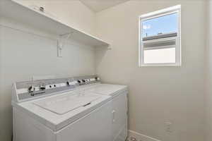Laundry room with washer and clothes dryer and baseboards