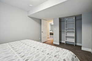 Bedroom with dark carpet, a closet, and a textured ceiling