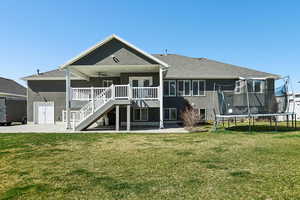 Rear view of house with a patio area, a ceiling fan, a yard, and a trampoline