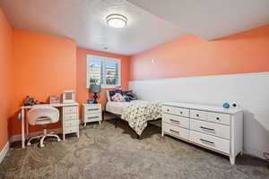 Bedroom featuring a textured ceiling, dark colored carpet, and a wainscoted wall