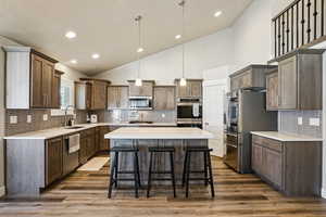 Kitchen with stainless steel appliances, a breakfast bar area, decorative backsplash, a center island, and lofted ceiling