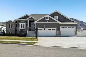 Craftsman house featuring board and batten siding, driveway, a front yard, brick siding, and a gate