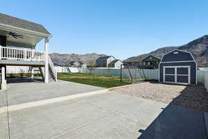 Fenced backyard featuring a mountain view, a patio area, ceiling fan, and a residential view