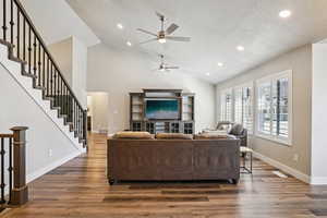 Living area with dark wood-style flooring, a ceiling fan, recessed lighting, and a high textured ceiling