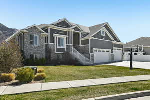 Craftsman-style house featuring board and batten siding, brick siding, a front lawn, and concrete driveway