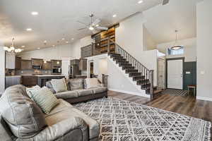 Living room with a ceiling fan, lofted ceiling, a chandelier, and dark wood finished floors