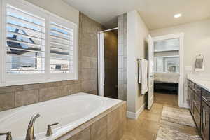 Full bathroom featuring connected bathroom, a shower stall, vanity, and a garden tub