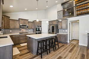 Kitchen with dark wood finish cabinetry, a kitchen bar, decorative backsplash, dark wood finished floors, and stainless steel appliances