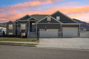 Craftsman-style house featuring board and batten siding, a gate, concrete driveway, brick siding, and a front lawn