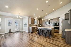 Kitchen featuring stainless steel appliances, a chandelier, a breakfast bar, a kitchen island, and dark wood finish cabinets