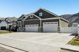Craftsman-style house with a gate, concrete driveway, board and batten siding, a mountain view, and an attached garage