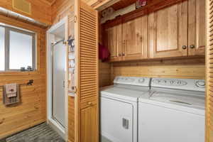Laundry room with wood walls, cabinet space, and washer and clothes dryer