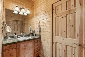 Half bath featuring wood walls and vanity