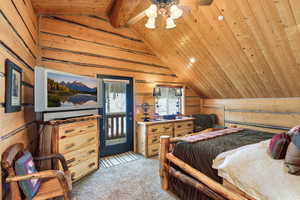 Bedroom with wooden walls, a wood ceiling with exposed beams, light colored carpet, access to exterior, and ceiling fan