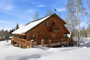Snow covered house featuring a wooden deck