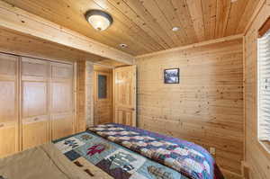 Bedroom with wood walls, wooden ceiling, and a closet