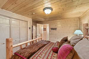 Bedroom with wood walls, a closet, and wooden ceiling