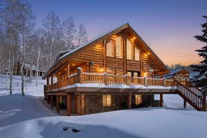 Rear view of house with log siding, a deck, and stone siding