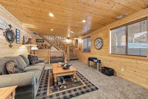 Carpeted living room with wood walls, wooden ceiling, and recessed lighting