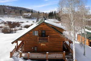 Snow covered rear of property with a wooden deck