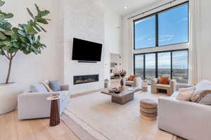 Living room featuring a high ceiling, light wood-style floors, and a fireplace