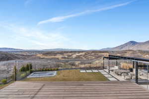 Wooden deck with a mountain view, a fenced backyard, and a patio