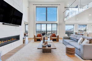 Living area with a high ceiling, a tiled fireplace, wood finished floors, healthy amount of natural light, and recessed lighting