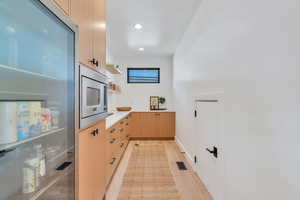 Kitchen featuring light wood finish cabinetry, open shelves, stainless steel microwave, recessed lighting, and light wood-type flooring