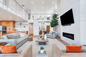 Living area with a high ceiling, wood finished floors, a tiled fireplace, and recessed lighting