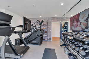 Workout room featuring brick wall and recessed lighting