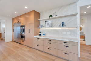 Kitchen with open shelves, recessed lighting, light wood finish cabinetry, stainless steel appliances, and light wood-style flooring